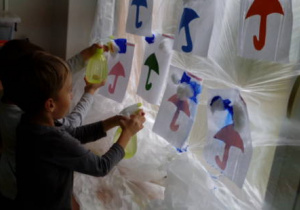 Dzieci podczas tworzenia kolorowego deszczu na szybie.
